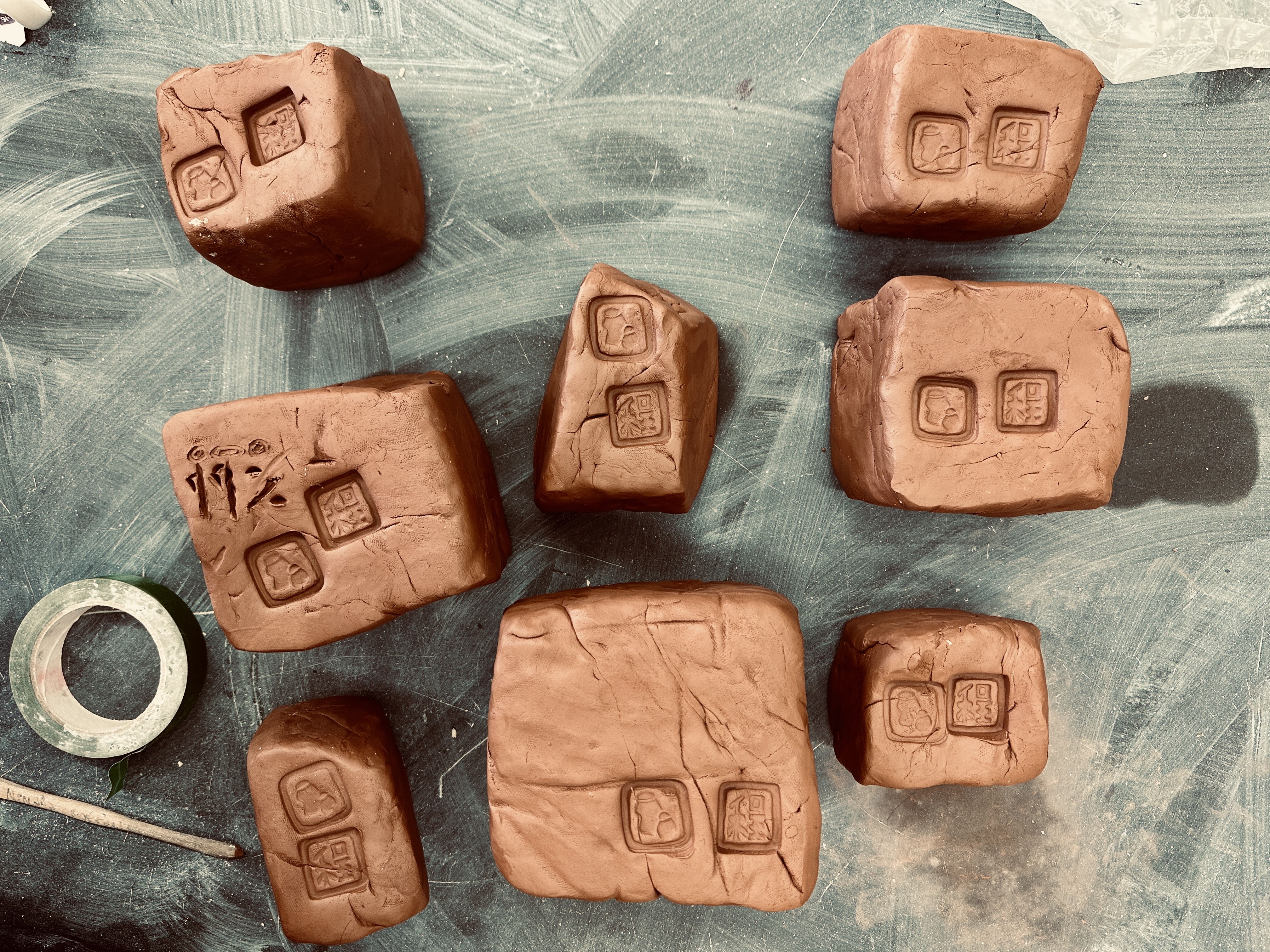 8 blocks of terracotta in the plastic stage of greenware. They are freshly wedged and stamped and ready for use.