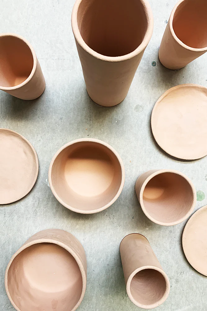 A top down photo of light beige bisqueware cups and plates.